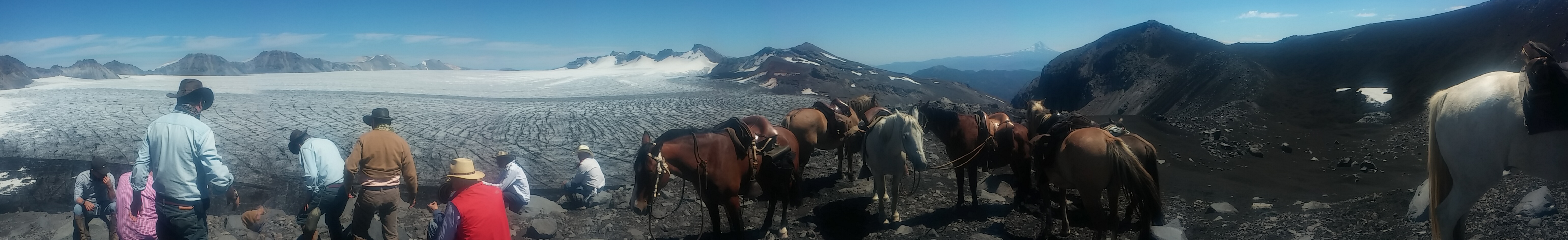 Riders and horses in front of the crater of Sollipulli 
